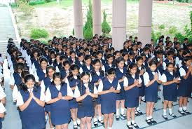Girls in uniform praying during school assembly