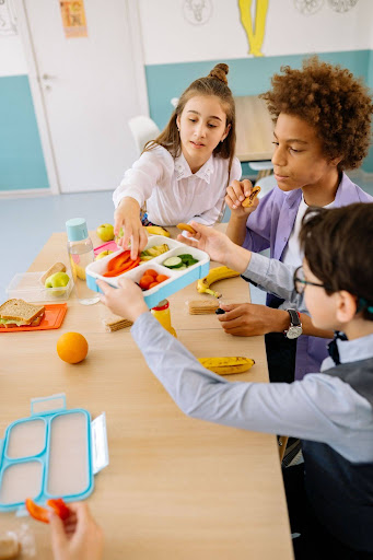 Students sharing healthy fruits and snacks during school meal time