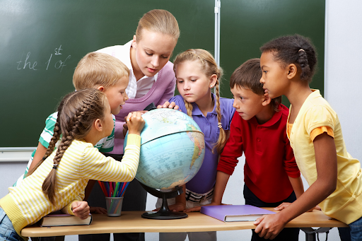 Teacher guiding students with a globe