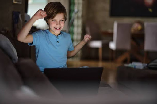 Child celebrating success during online learning session