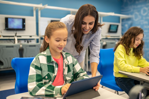 Teacher assisting students using tablets in class