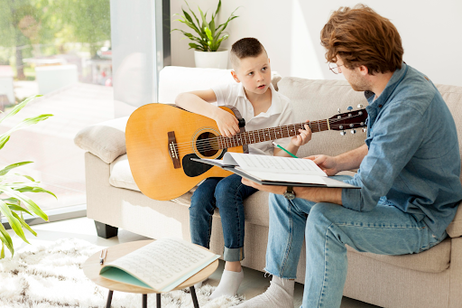 Teacher guiding a child during a guitar lesson
