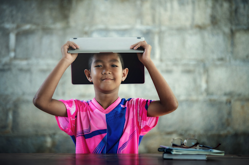 Child holding a laptop above their head