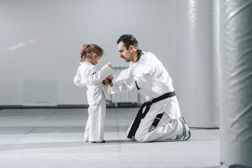 Karate instructor guiding a young child during a martial arts training session